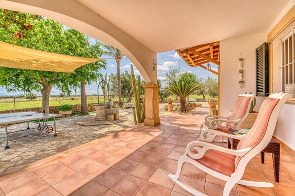 Une terrasse extérieure avec un sol en pierre, une table, des chaises et une pergola offrant de l’ombre.
