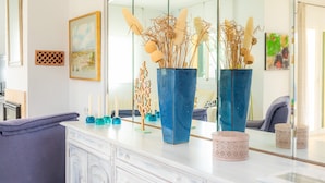 A modern bathroom with a white vanity, two blue vases with dried plants, a mirror, and a framed picture on the wall. - Villa 'La Vinya del Beato 1950' with Mountain Views, Private Pool, and Garden (Port de Pollença)