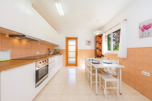 Een moderne keuken met witte kastjes, een houten aanrecht en een eethoek met een witte tafel en stoelen.