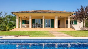 A house with a swimming pool, a covered patio with chairs, and a lawn. - Villa 'La Vinya del Beato 1950' with Mountain Views, Private Pool, and Garden (Port de Pollença)