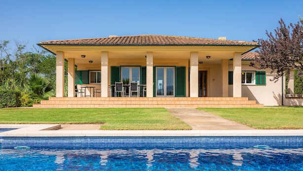 A house with a swimming pool, a covered patio with chairs, and a lawn. - Villa 'La Vinya del Beato 1950' with Mountain Views, Private Pool, and Garden (Port de Pollença)