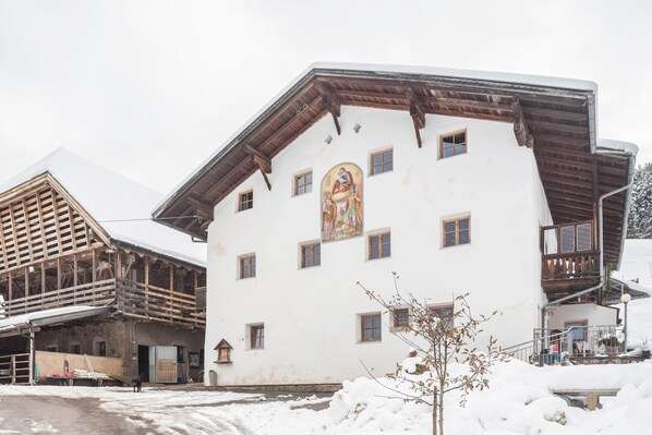 A building with a large mural, wooden balconies, and a snow-covered ground.