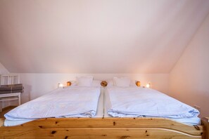 Een tweepersoonsbed met houten frame, twee nachtkastjes en een hoofdbord.