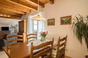 Un coin repas avec une table en bois, des chaises, un luminaire suspendu et une plante en pot.