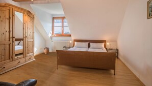 Ein Schlafzimmer mit Bett, Holzschrank und Fenster mit Blick.