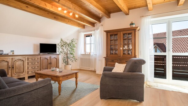 Ein Wohnzimmer mit Holzbalken, einem Fernseher, einem Schrank, einem Sofa und einem Fenster.