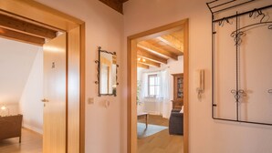 Ein Flur mit Holzboden, einer Holztür, einem Spiegel und einem an der Wand befestigten Telefon.