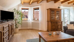 Ein Wohnzimmer mit Fernseher, Holzschrank und Topfpflanze.