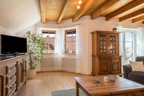 Un salon avec un téléviseur, un meuble en bois et une plante en pot.