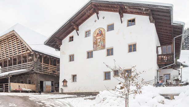 Edifici amb un mural gran, balcons de fusta i un sòl cobert de neu.