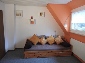 Habitación acogedora con sofá cama de madera, ventana con vistas y un radiador.
