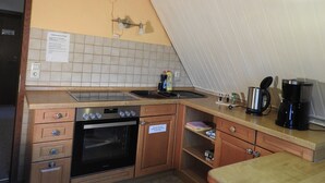 Una cocina compacta con horno integrado, pileta y cafetera.
