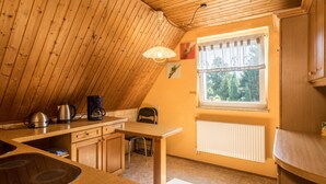 Una cocina con armarios de madera, estufa, cafetera y ventana con vistas a árboles.