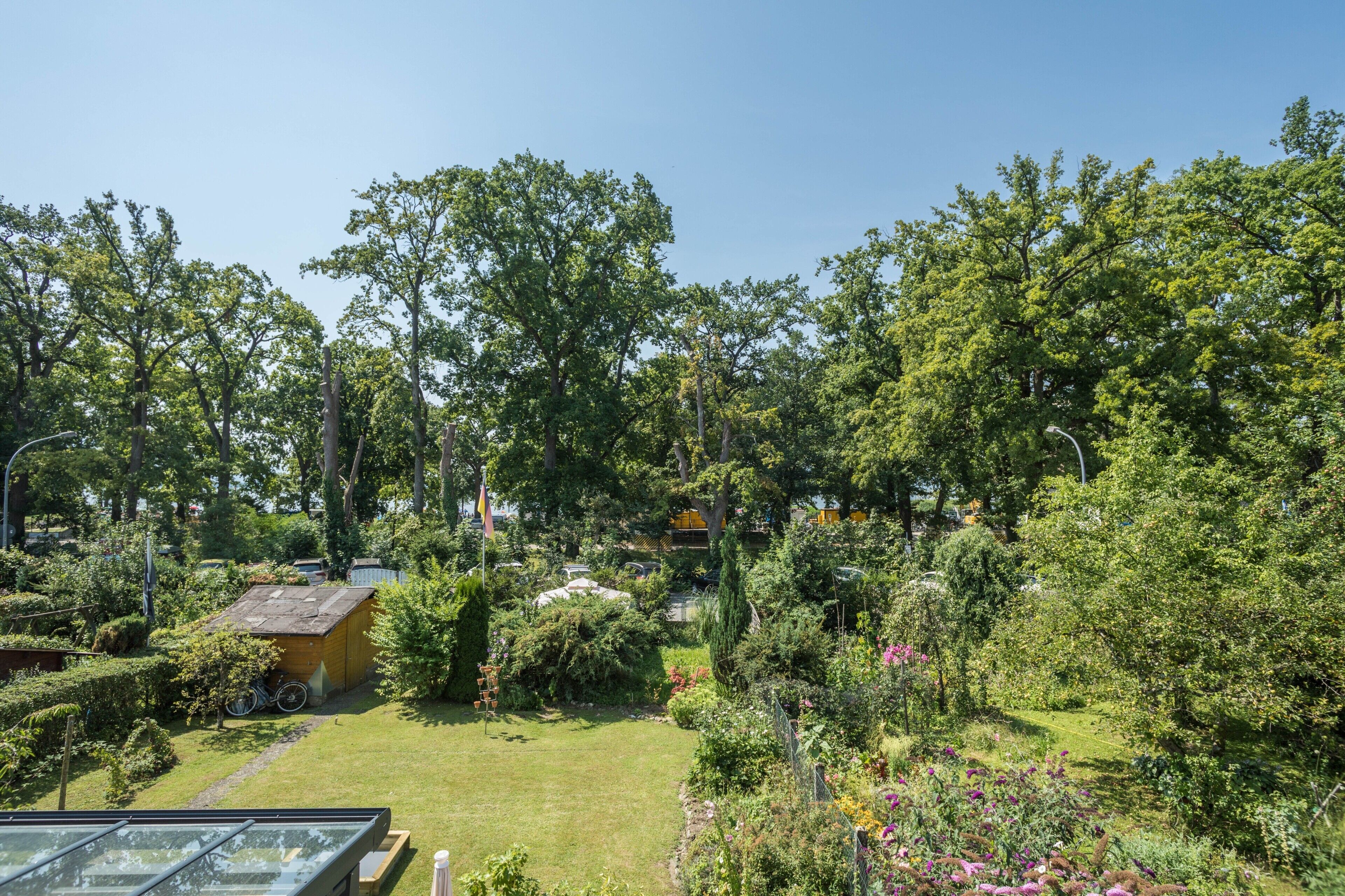 Ein Garten mit einer Holzkonstruktion, einem Fahrrad und blauem Himmel.