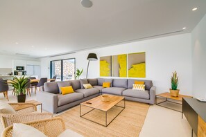 Uma sala de estar moderna com um sofá seccional, uma mesa de centro e um espaço de jantar com cadeiras.
