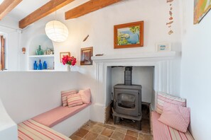 Una habitación acogedora con chimenea, un banco y una estantería con adornos.