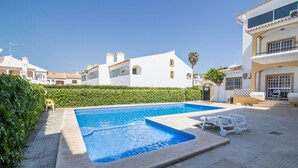 A swimming pool with lounge chairs, a hedge, and white buildings with balconies. - Beautiful Marjoh AL Holiday Apartment with Pool, Balcony, Air Conditioning and Wi-Fi (Vilamoura, Quarteira)