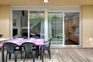 A dining area with a table set for four, a sliding glass door leading to a patio, and a kitchen visible through the door. - “Casa Vacacional en Caños de Meca” with Shared Pool (Caños de Meca)