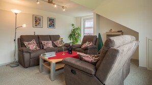 A living room with two sofas, a coffee table, a floor lamp, and a window with curtains. - High-Quality Apartment “Ferienwohnung Steinhilber 1” (Eriskirch)