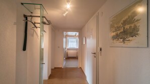 A hallway with a glass shelf, a door, and a painting on the wall. - High-Quality Apartment “Ferienwohnung Steinhilber 1” (Eriskirch)