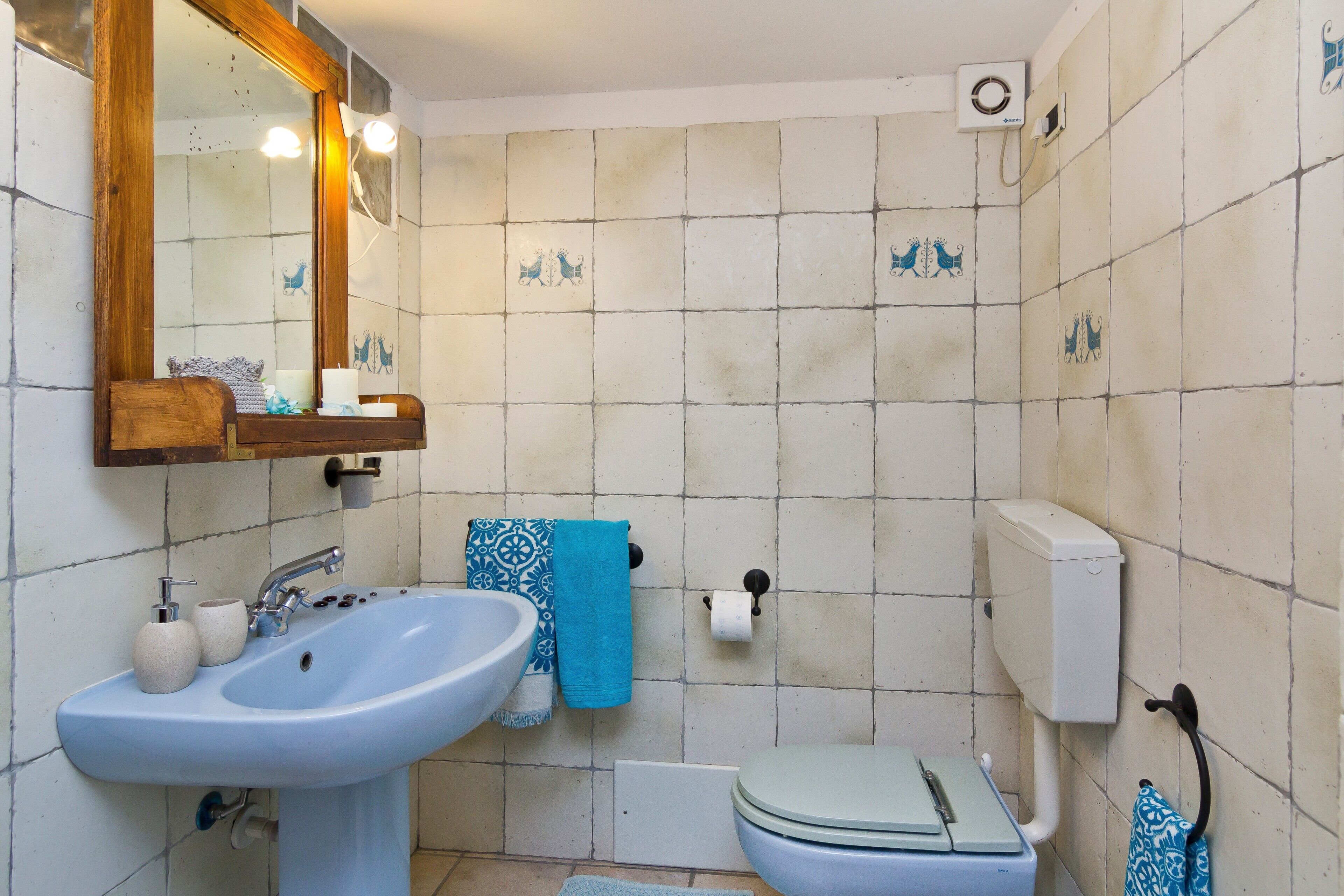 Une salle de bain équipée d’un lavabo, d’un miroir, de toilettes et d’un porte-serviettes.