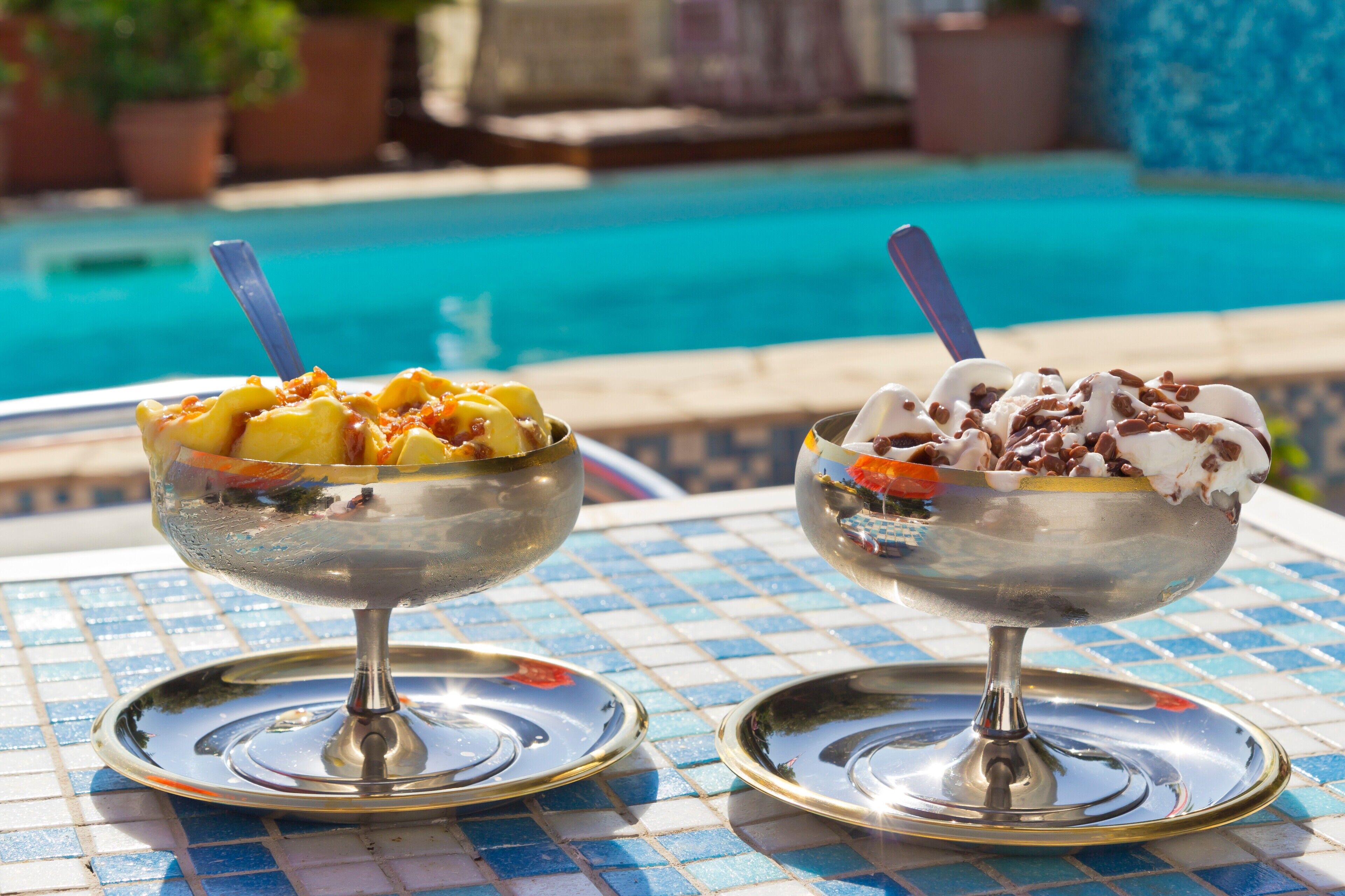 Two dessert bowls on a tiled table by a poolside.