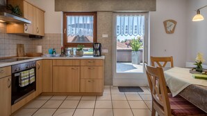 A kitchen with wooden cabinets, a stove, and a window overlooking a residential area.