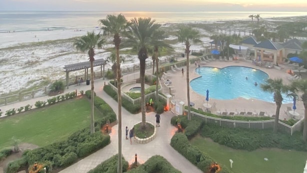 Ein Resort mit großem Pool, Palmen und Blick auf den Strand.