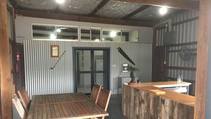 A rustic wooden dining table with chairs, a bar counter, and a small potted plant.