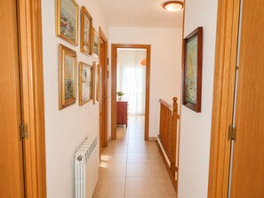 A hallway with wooden doors, a radiator, and framed pictures on the walls. - Charming Sitges Apartment with Shared Pool & City Views (Sitges)
