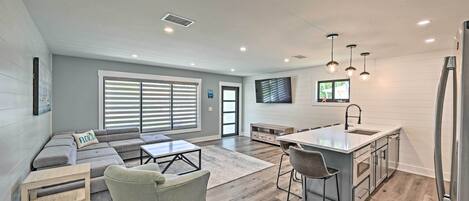 A modern kitchen with a central island, bar stools, and a built-in sink.
