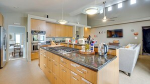A modern kitchen with wooden cabinets, a central island, stainless steel appliances, and pendant lighting. - Walk to Seaside Beach! House w/ Hot Tub & Deck (Seaside)