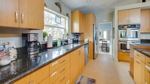 A modern kitchen with wooden cabinets, stainless steel appliances, and a granite countertop. - Walk to Seaside Beach! House w/ Hot Tub & Deck (Seaside)