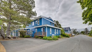 A two-story blue house with a front porch, a driveway, and a street view. - Walk to Seaside Beach! House w/ Hot Tub & Deck (Seaside)