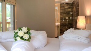 A hotel room with two beds, a shower area, and a view of the outdoors.