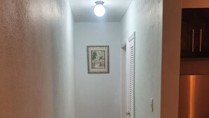 A narrow hallway with a light fixture, a framed picture on the wall, and a refrigerator on the right. - Cozy Villa in Nassau with homely feel in quiet neighborhood.  (Nassau)