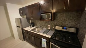 A kitchen with dark wooden cabinets, a stainless steel refrigerator, a microwave, a double sink, and a gas stove. - Cozy Villa in Nassau with homely feel in quiet neighborhood.  (Nassau)