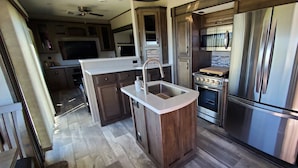 A modern kitchen with a central island, stainless steel appliances, and a microwave above the oven.