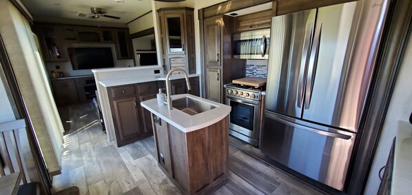 A modern kitchen with a central island, stainless steel appliances, and a microwave above the oven.