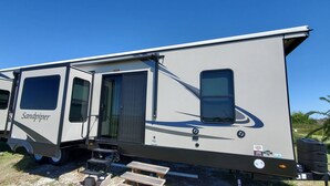 A large RV with a sliding door, a small step-up platform, and a logo on the side.