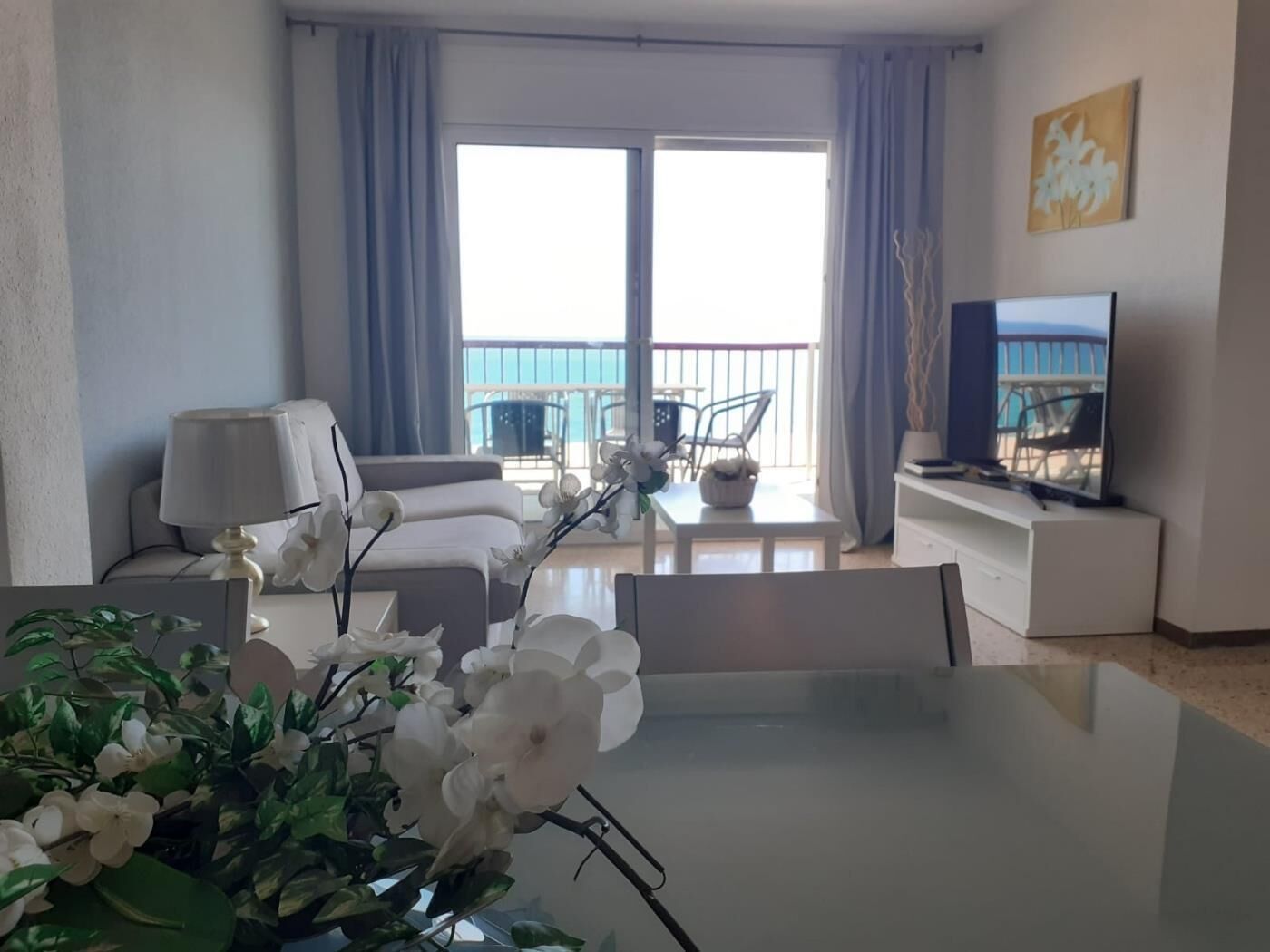 Una sala de estar moderna con balcón, un comedor y un televisor.