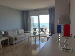 Ein modernes Wohnzimmer mit einem weißen Sofa, einem Couchtisch und einem Balkon mit Meerblick.