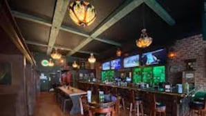 Een bar met houten vloeren en hangende lampen.