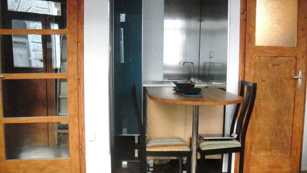 A small kitchen with a round table and two chairs, a wooden cabinet, and a door with glass panels. - THE TOTAL APPARTMENT IS YOURS ALONE (BUDAPEST)