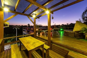 Relax on the outdoor deck with a clear view of the surrounding landscape, featuring comfortable seating and a glass enclosure.