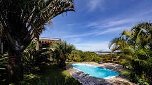 A swimming pool surrounded by lush greenery and a stone deck.