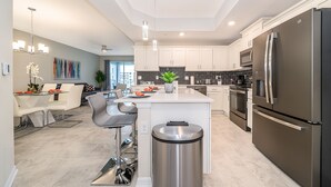 Una cocina moderna con armarios blancos, electrodomésticos de acero inoxidable y una isla central.