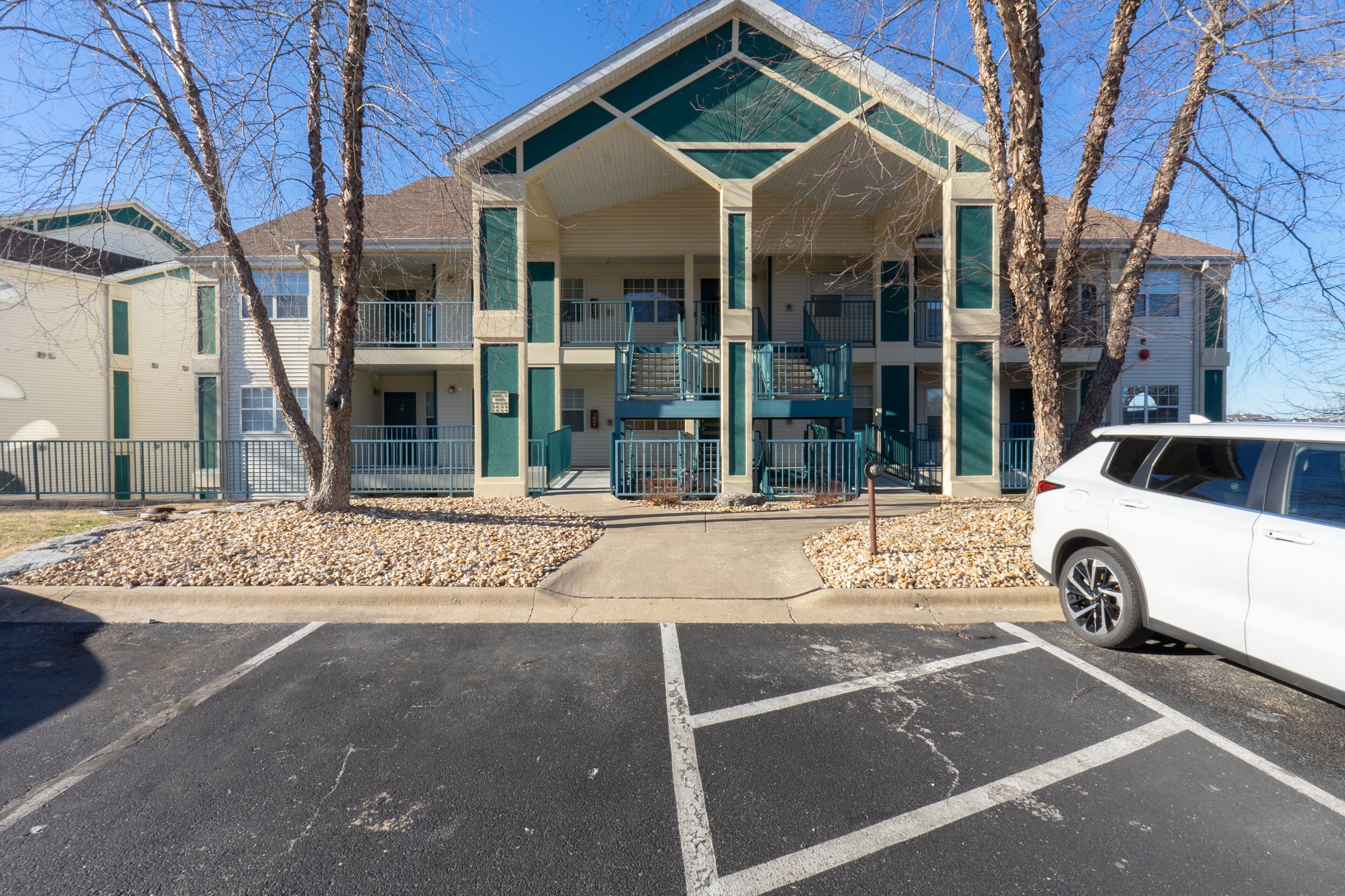 A multi-story building with a central atrium, outdoor parking, and a white car parked in front.