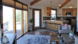 A spacious living area with a large sliding glass door, a kitchen with wooden cabinets and a central island, and a cozy seating area with a patterned rug. - Little Ranch Home near National Parks & Lake Powell (Clark Bench)