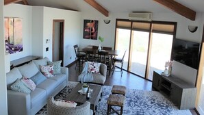 A spacious living room with a high ceiling, a dining area, and a large sliding glass door leading to a balcony. - Little Ranch Home near National Parks & Lake Powell (Clark Bench)